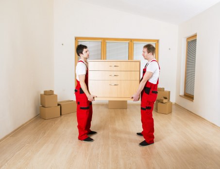 Removal team carrying boxes through a narrow staircase in a London flat